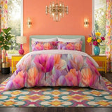Vista frontale del completo letto matrimoniale Botticelli Home modello Ninfea Splendor con lenzuolo in puro cotone a motivi floreali grandi in una stanza colorata.