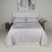Copriletto matrimoniale elegante Battaglia modello Laura grigio perla steso sul letto.