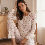 Modella seduta che indossa il pigiama da donna a costine con fantasia floreale rosa e scollo a serafino con bottoncini