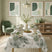 Tavola apparecchiata in stile moderno naturale con la tovaglia Aura verde con stampe di grandi foglie e fiori verdi.